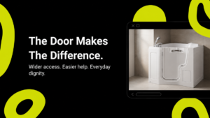 The Denton 1300 Wheelchair Accessible Walk-In Bath with its side-entry door fully open, showing the wide door aperture and moulded interior seat in a calm UK domestic bathroom.