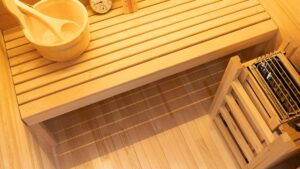 Inside the Vidalux Klassikko traditional sauna with cedar bench, wooden bucket and ladle, and stone-filled heater