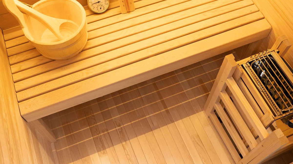 Inside the Vidalux Klassikko traditional sauna with cedar bench, wooden bucket and ladle, and stone-filled heater