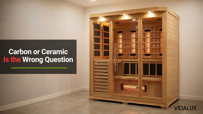 Vidalux 4-5 person infrared sauna cabin with visible glowing infrared heaters, installed freestanding in a finished home wellness room with concrete flooring and warm ambient lighting.