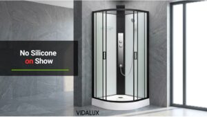 Vidalux Kontrast 800 Square shower cabin with black frame and white glass panels installed in the corner of a grey-tiled bathroom.
