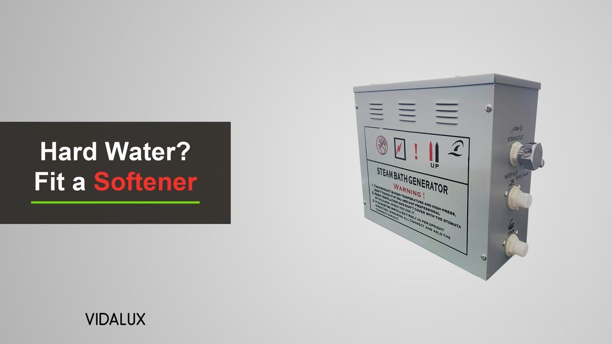 A Vidalux steam room generator, a silver-grey metal box with the steam outlet and water inlet fittings on its side, on a light grey background.
